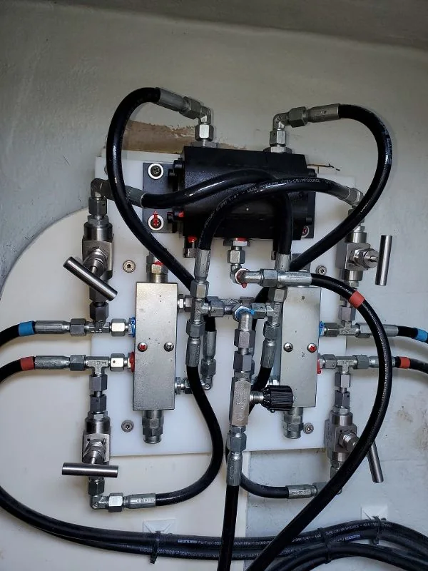 Marine hydraulic manifold and valve assembly mounted on a white equipment panel
