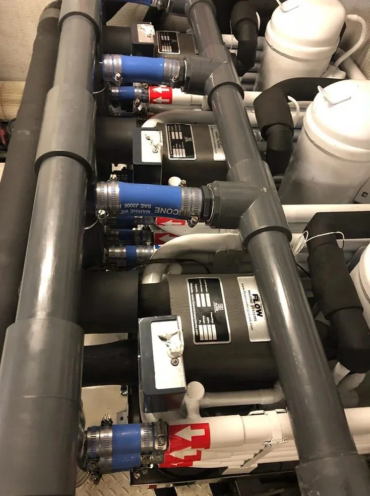 Installed marine chilled-water equipment connected to piping and blue hose couplings.