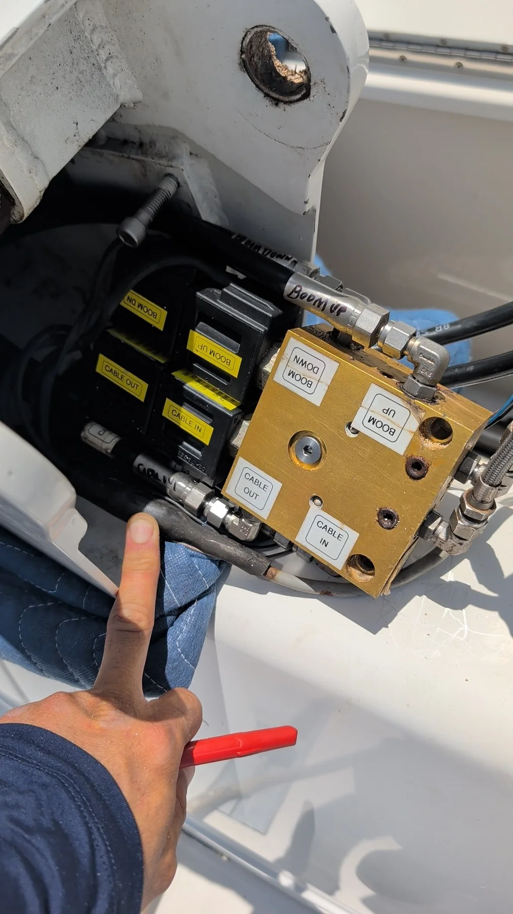 Technician identifying labeled boom and cable circuits on a davit hydraulic manifold