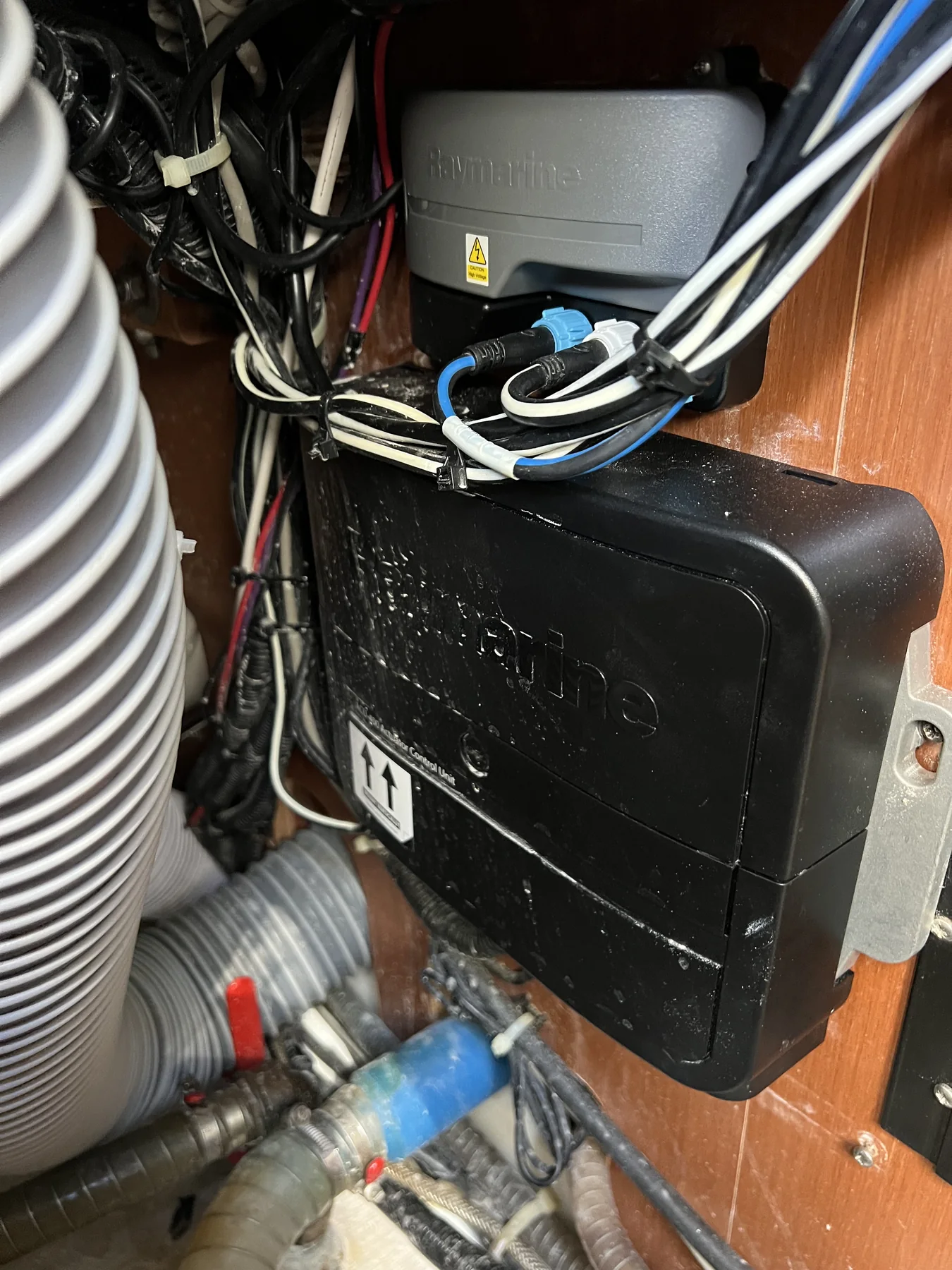 Raymarine autopilot actuator control unit mounted beside wiring and hose.
