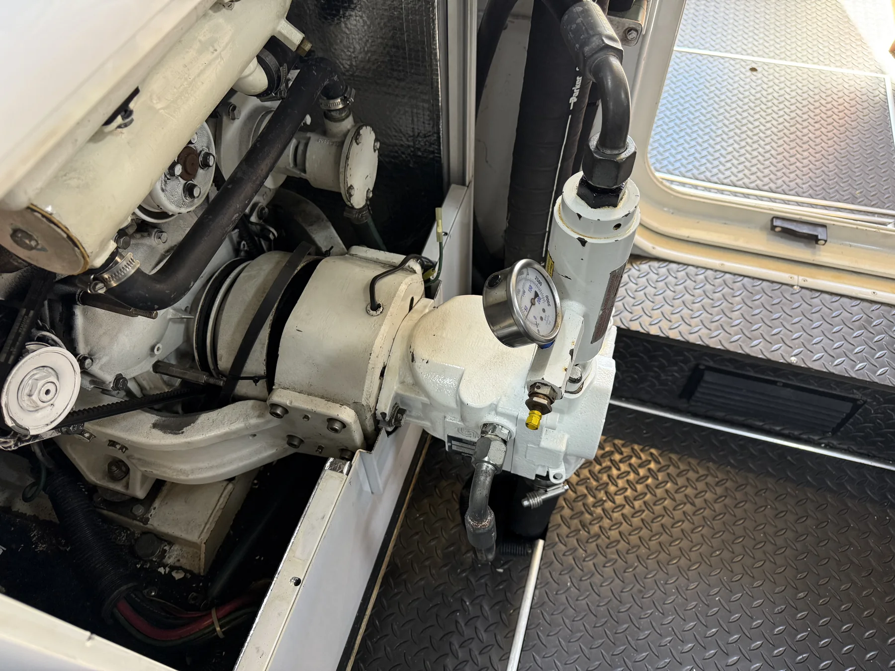 Marine pump or PTO assembly with connected hose and pressure gauge.