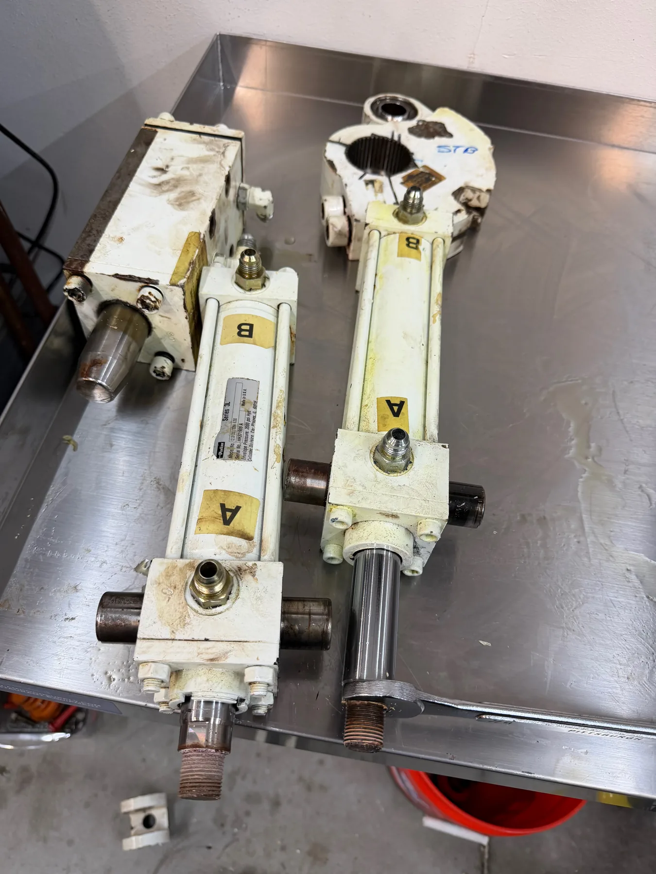 Cylindrical marine hardware and a round component on a stainless-steel shop workbench.