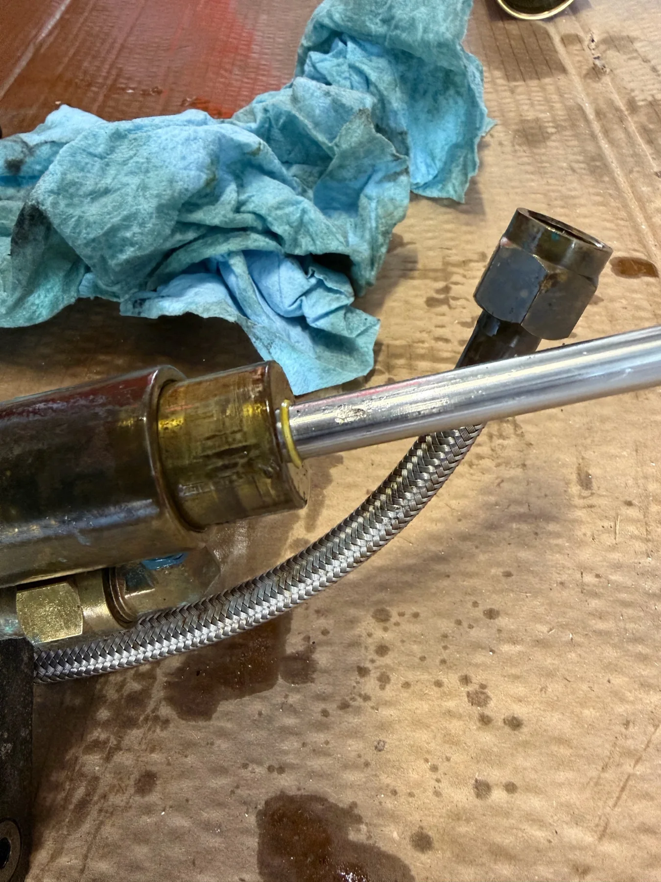Partially disassembled marine hydraulic cylinder with exposed rod and braided hose