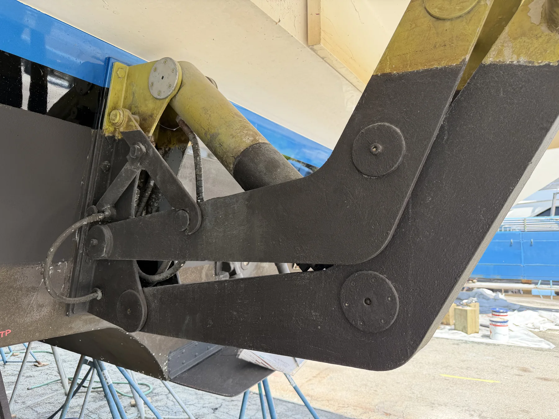 Hydraulic cylinder with hoses and the lift-arm linkage of a swim platform.