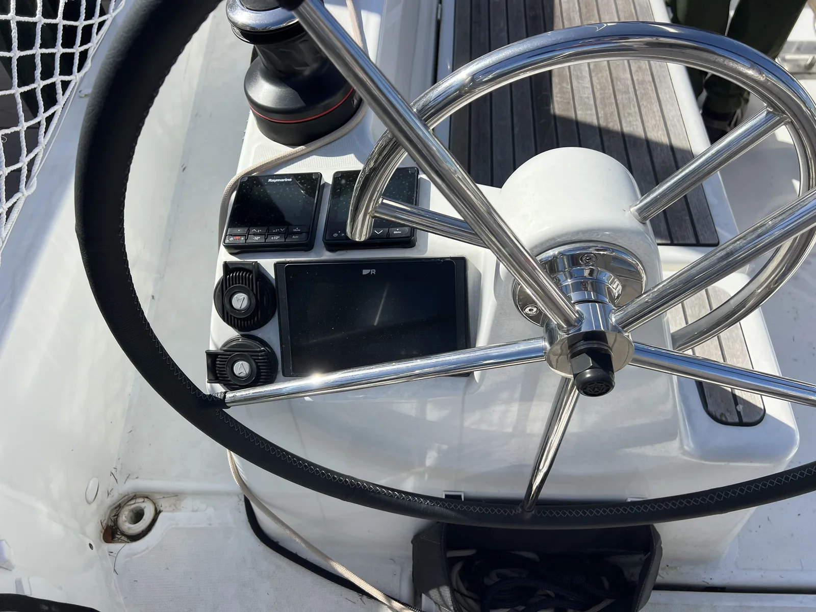 Marine electronics displays and controls at a sailboat helm.