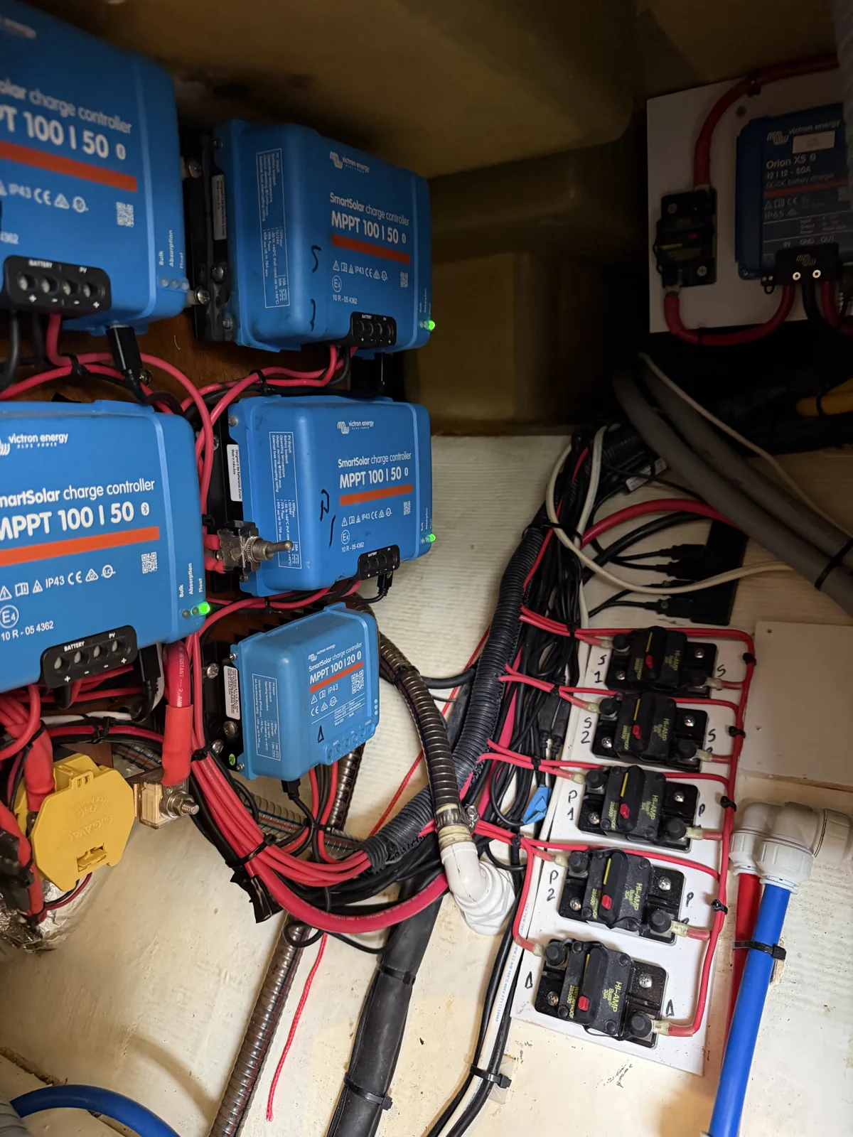 Victron SmartSolar MPPT controllers beside connected wiring and circuit protection.
